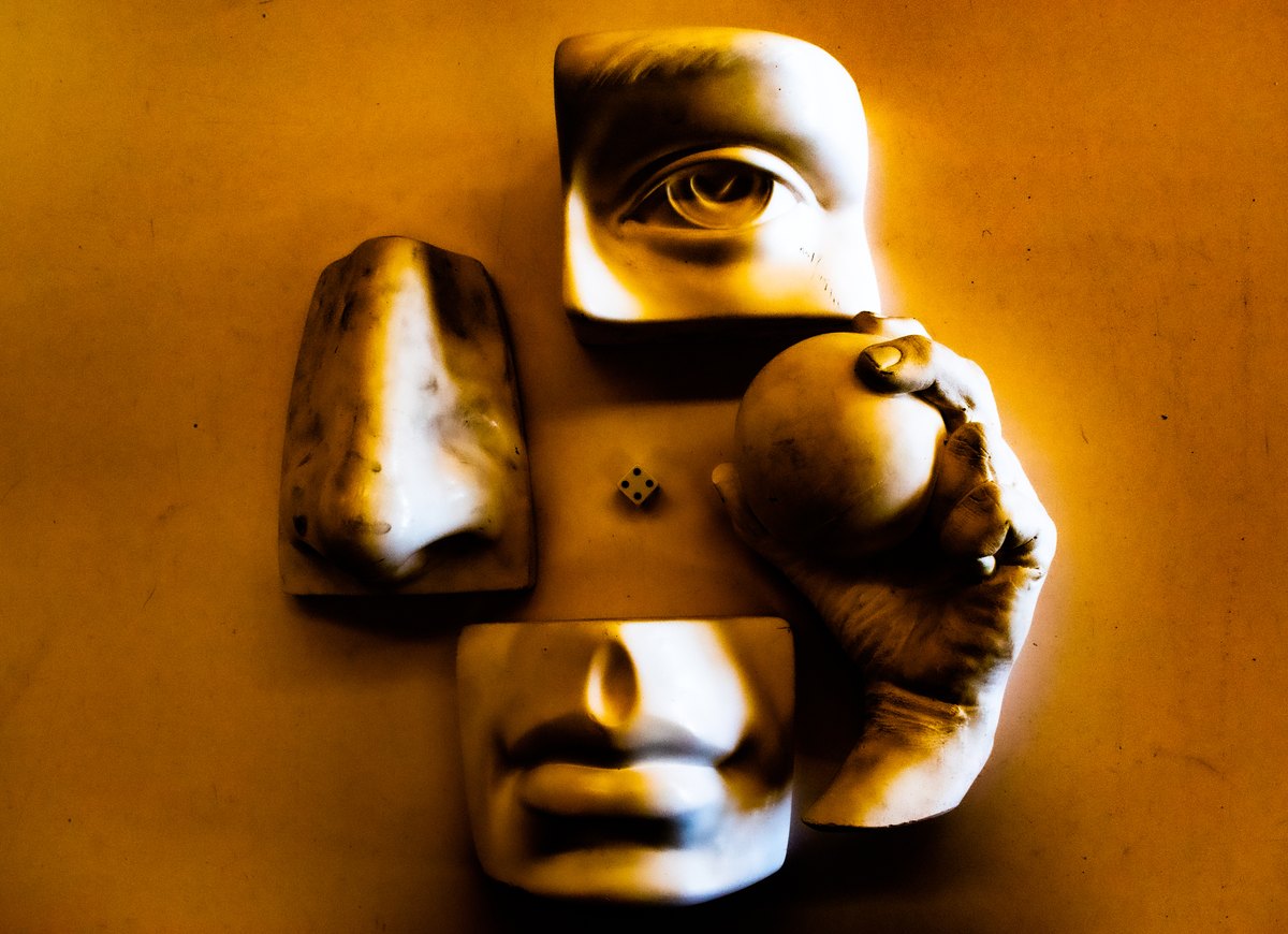 Fragments of sculpted faces arranged against a golden background.