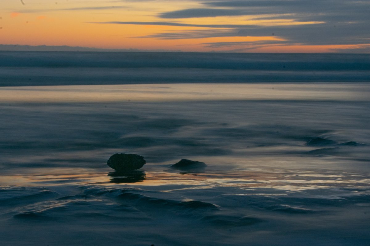 Ocean waves and dark rocks at sunset in Monterey.